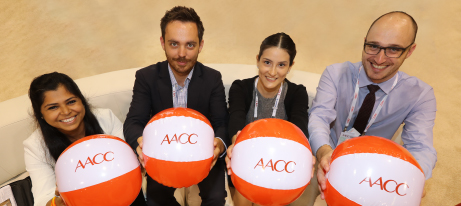 Four people holding balls marked with the AACC logo.