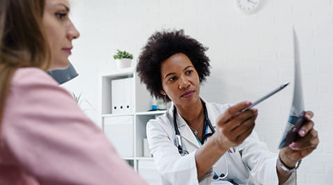 Physician points to a paper with a pen while patient looks on