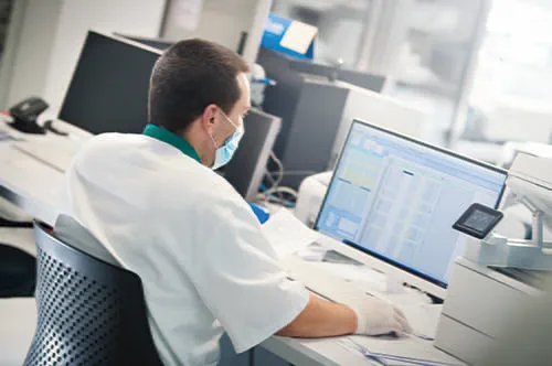 A male laboratorian sitting at a desk on a computer