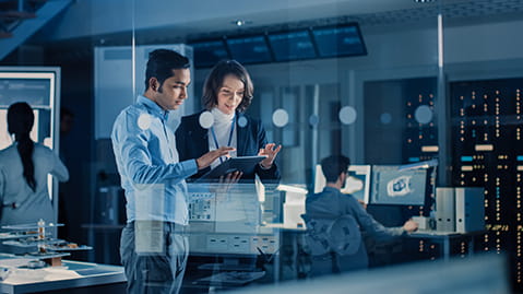A male and female in a lab, looking at a tablet, and surrounded by transparent views from around the lab.